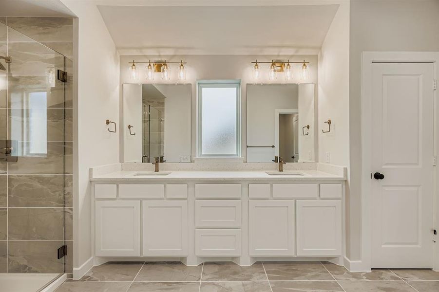 Full bathroom featuring a shower stall, double vanity, and marble look tiles