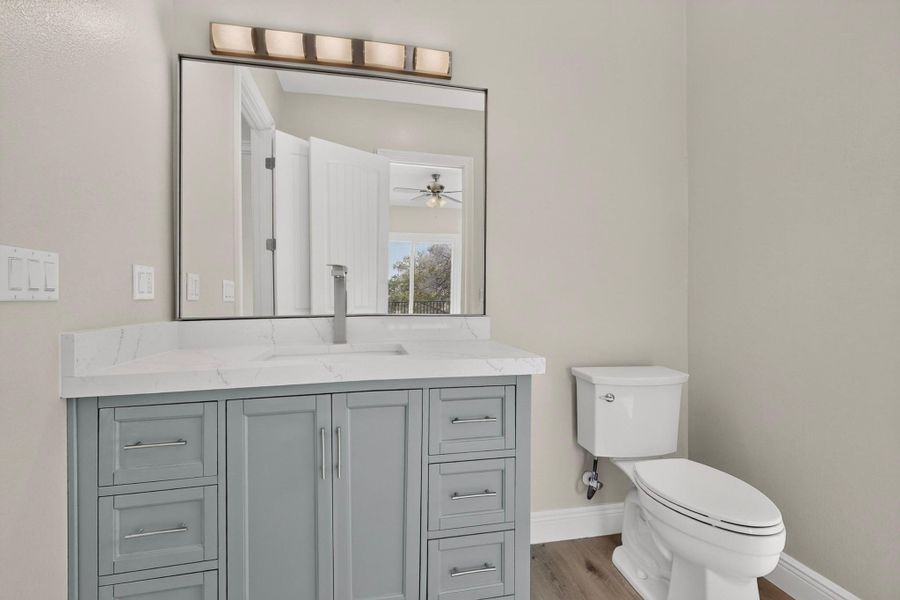 A modern vanity with a stone countertop sits beside a classic white commode.