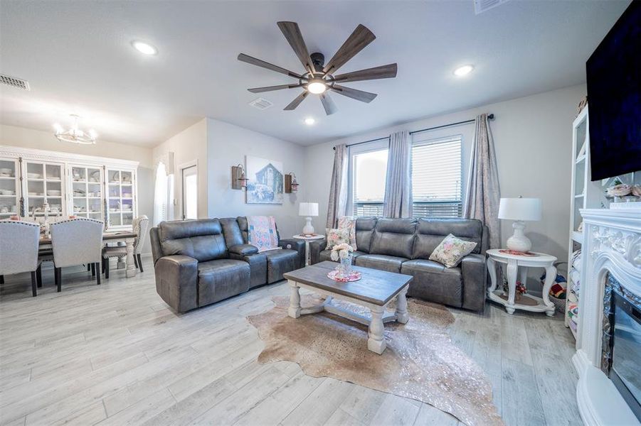 Living room featuring ceiling fan with notable chandelier, light hardwood / wood-style floors, and a premium fireplace