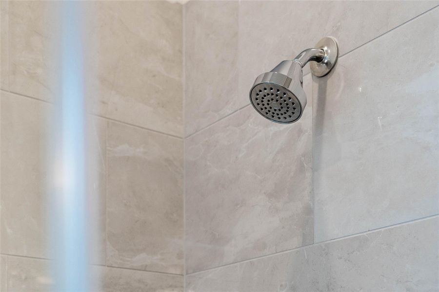 Enjoy a spa-like experience in this modern walk-in shower featuring a sleek chrome fixed shower head and elegant porcelain tile surround.