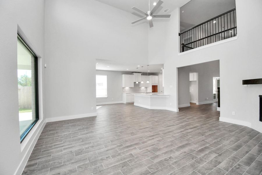 Welcome family and guests to your charming living room! With its high ceilings, recessed lighting, ceiling fan, custom paint, beautiful flooring, and large windows that let in abundant natural light, this room is perfect for gatherings.