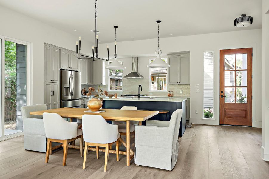 Kitchen featuring stainless steel fridge, wall chimney exhaust hood, tasteful backsplash, and light wood finished floors