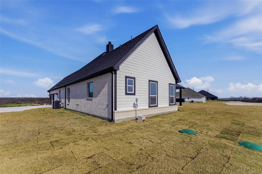 View of side of home with brick siding, a yard, and a chimney