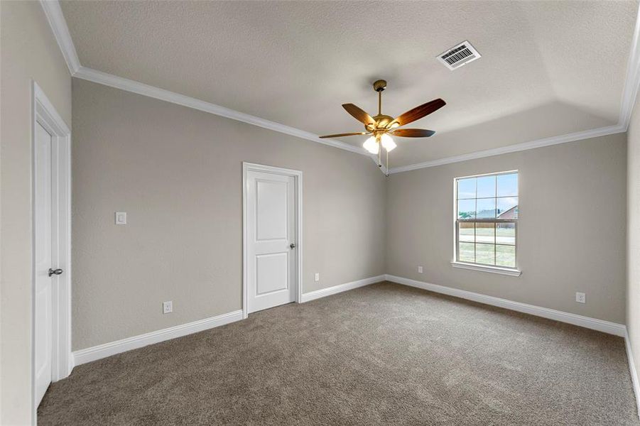 Carpeted room featuring a ceiling fan with light fixture, tray ceiling, crown molding, and white trim