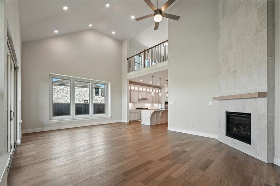 Unfurnished living room with recessed lighting, a fireplace, dark wood finished floors, high vaulted ceiling, and a ceiling fan Unfurnished living room with recessed lighting, a fireplace, dark wood finished floors, high vaulted ceiling, and a ceiling fan