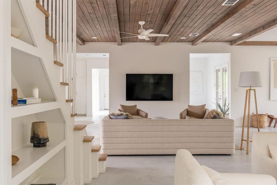 Living room featuring built in features, healthy amount of natural light, concrete floors, and a wood ceiling with exposed beams Living room featuring built in features, healthy amount of natural light, concrete floors, and a wood ceiling with exposed beams