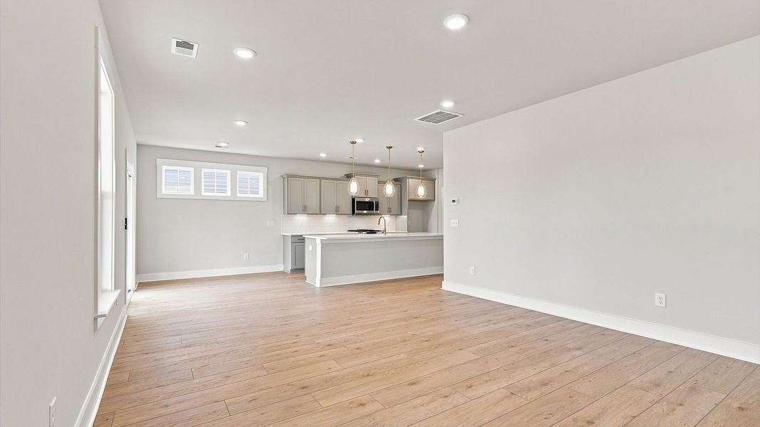 Elegant family room featuring hardwood flooring, large windows, and thoughtful architectural detail Elegant family room featuring hardwood flooring, large windows, and thoughtful architectural detail
