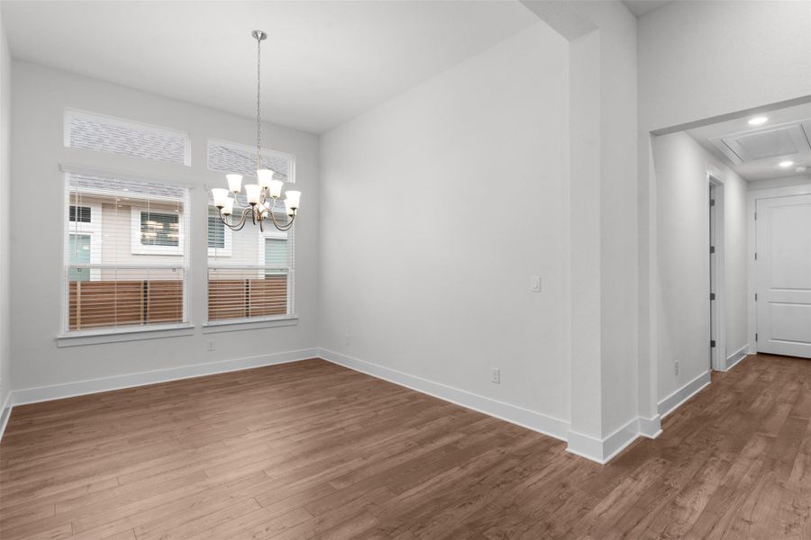 Unfurnished dining area featuring wood finished floors, a chandelier, attic access, and recessed lighting