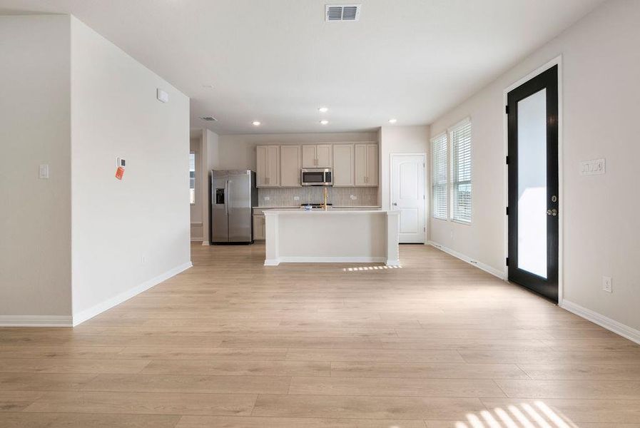 Kitchen featuring a kitchen island with sink, light countertops, stainless steel appliances, light wood finished floors, and open floor plan