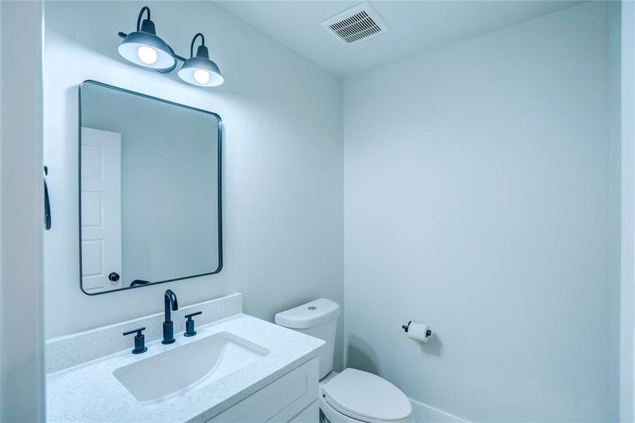 Bathroom vanity with a rectangular mirror, a light-toned countertop, and a built-in sink with matte black fixtures