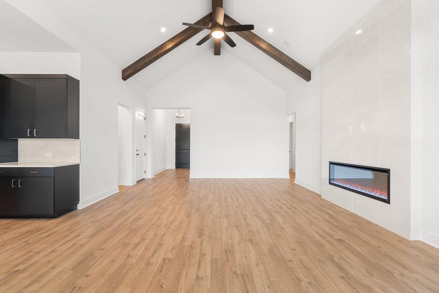 Vaulted ceilings with exposed beams and a linear fireplace enhance this generously sized gathering space.