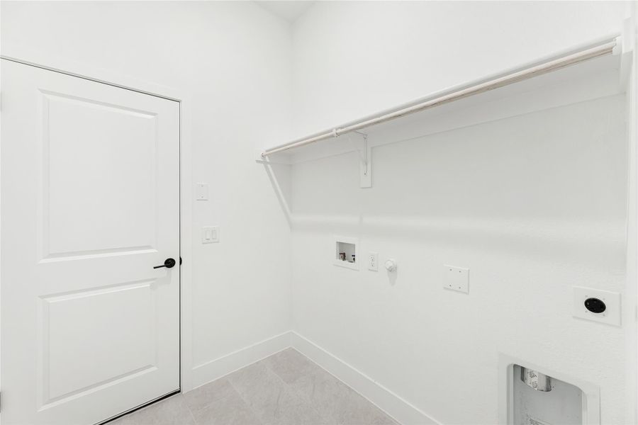 Laundry room with upper shelf, washer and dryer hookups, and white walls and tile floor