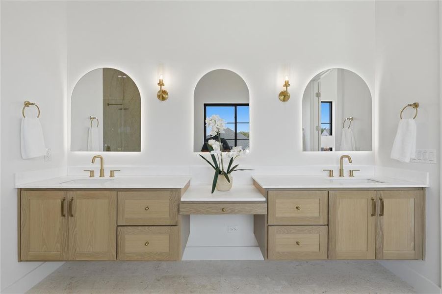 Dual floating wood-finish vanities featuring light stone countertops and brushed gold fixtures
