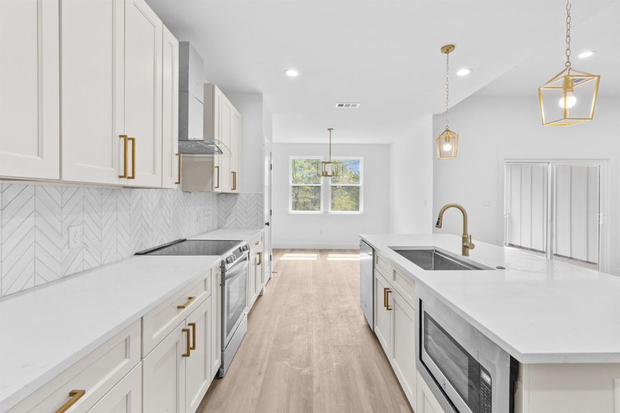 Kitchen featuring stainless steel appliances, decorative light fixtures, decorative backsplash, a center island with sink, and recessed lighting