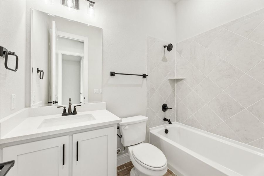 Full bathroom with white vanity, tub-shower combo with diagonal tile, and black hardware accents Full bathroom with white vanity, tub-shower combo with diagonal tile, and black hardware accents
