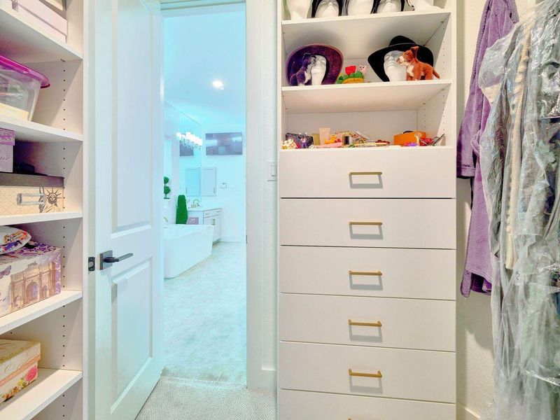 Discover the perfect his-and-hers walk-in closets, complete with custom shelving and drawers for ultimate organization.