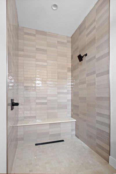 Tiled shower enclosure featuring a linear drain, integrated bench seating, and matte black fixtures