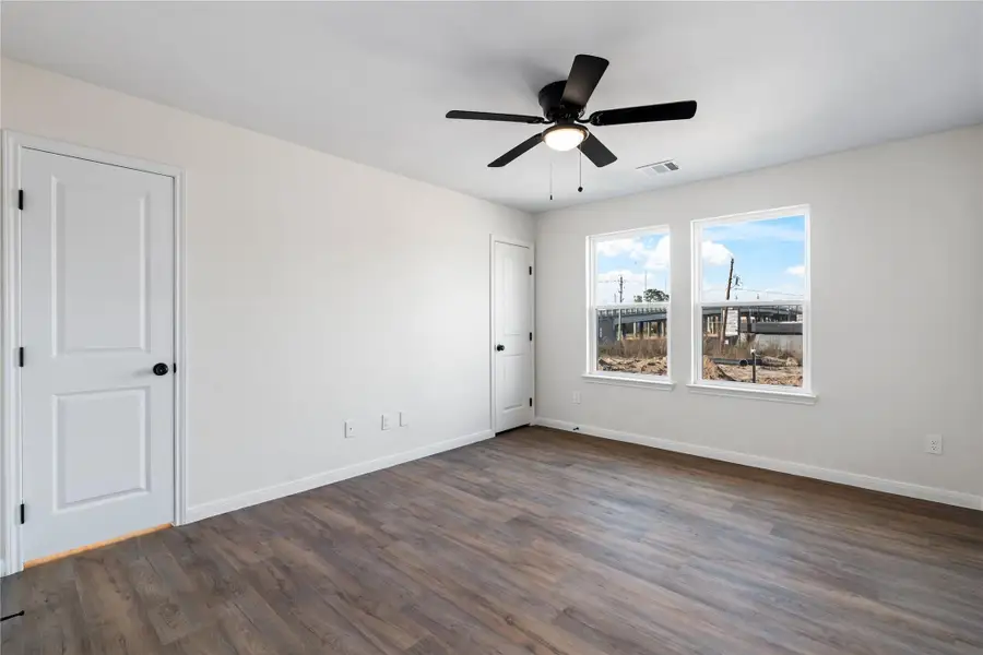The primary bedroom offers generous space and multiple windows, providing abundant natural light and a comfortable layout.