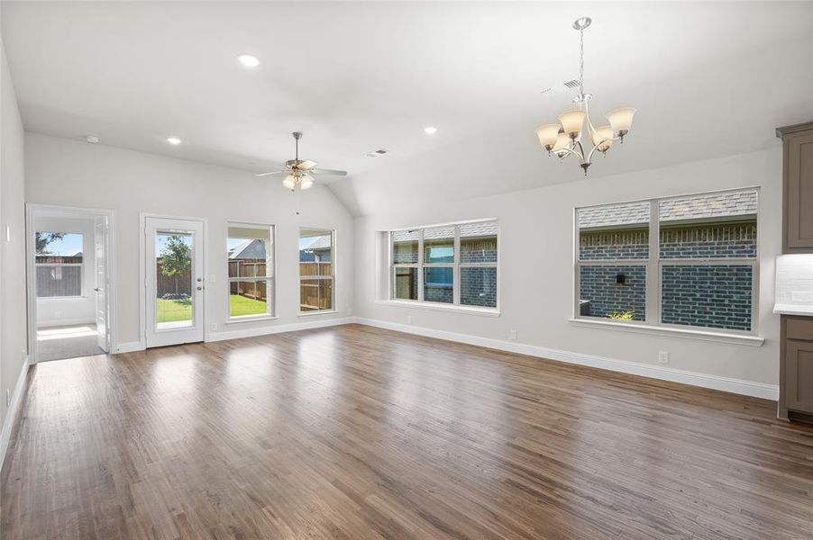 Unfurnished living room with dark wood-style flooring, recessed lighting, a chandelier, lofted ceiling, and ceiling fan