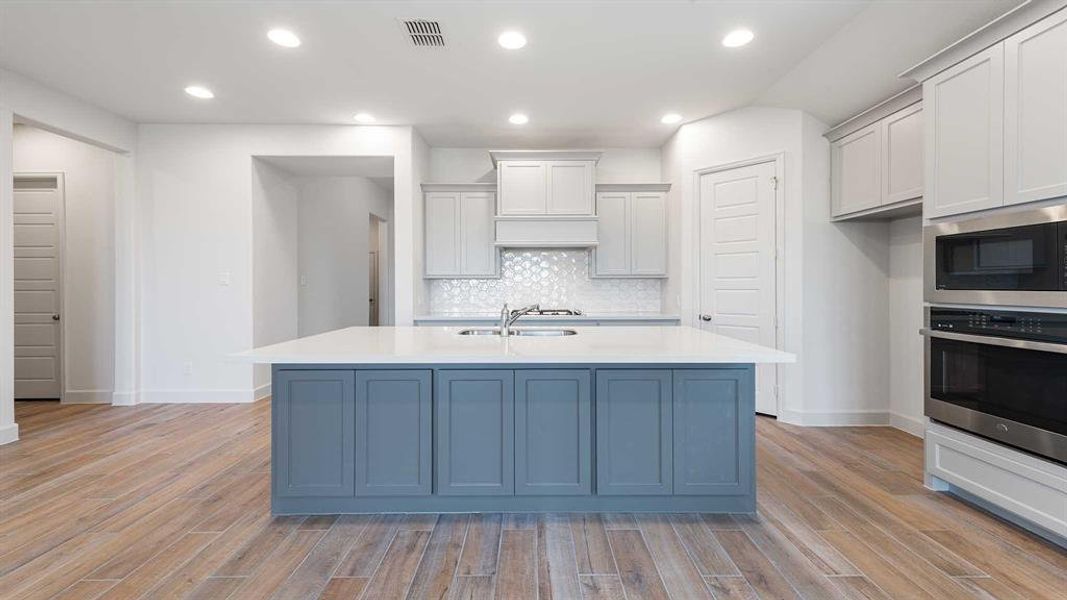 Kitchen with light wood-type flooring, stainless steel oven, white cabinets, and built in microwave