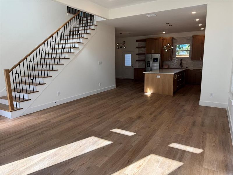 Kitchen featuring pendant lighting, stainless steel fridge with ice dispenser, dark hardwood / wood-style floors, and a center island