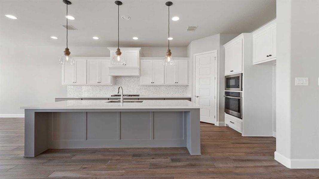 Kitchen featuring white cabinets, stainless steel appliances, dark hardwood / wood-style flooring, and a kitchen island with sink