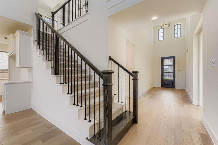 Foyer entrance featuring light wood-style flooring and a high ceiling Foyer entrance featuring light wood-style flooring and a high ceiling
