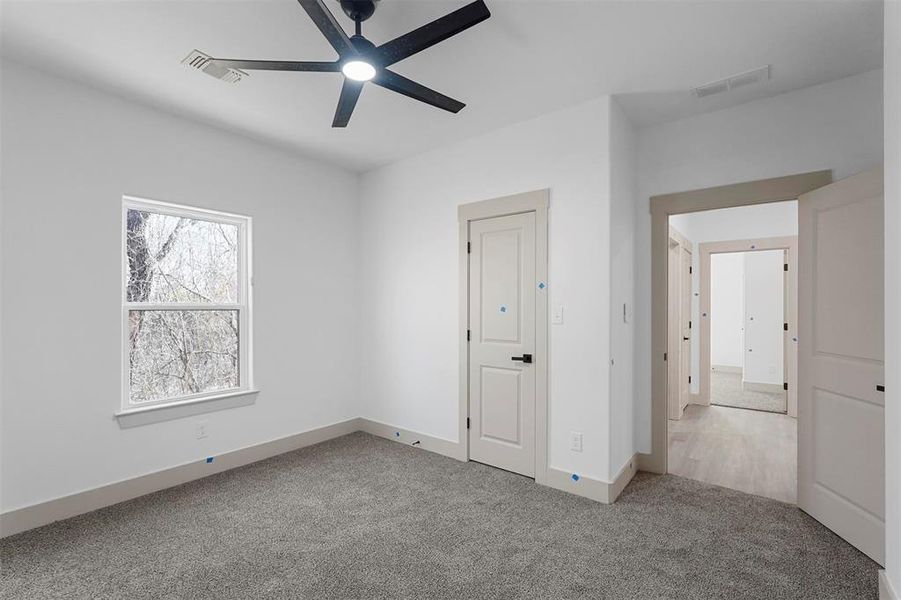 Unfurnished bedroom featuring visible vents, ceiling fan, baseboards, and carpet