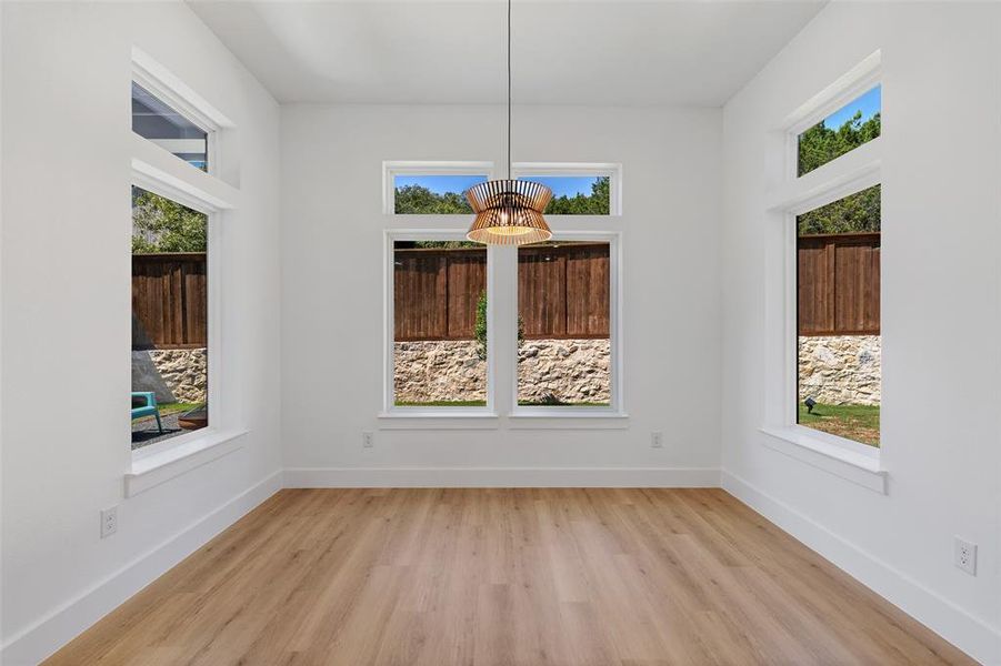 Unfurnished dining area featuring an inviting chandelier, light hardwood / wood-style flooring, and a wealth of natural light