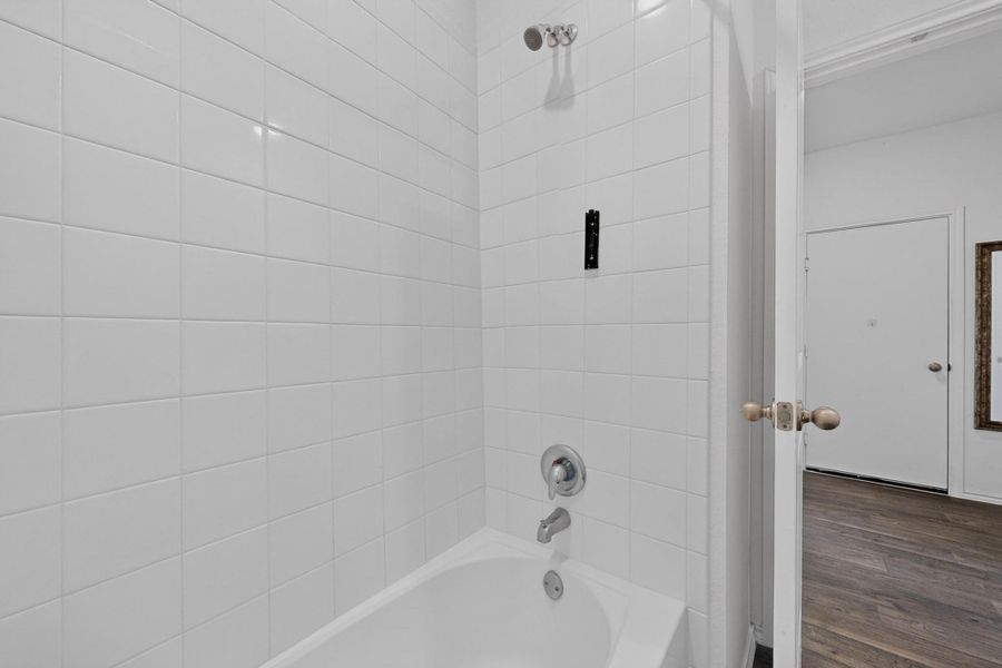 Tiled walls surround a clean bathtub, offering a glimpse into the adjacent living space. Tiled walls surround a clean bathtub, offering a glimpse into the adjacent living space.