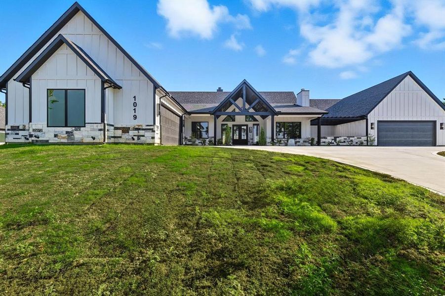 Modern farmhouse style home with board and batten siding, an attached garage, and a front lawn Modern farmhouse style home with board and batten siding, an attached garage, and a front lawn