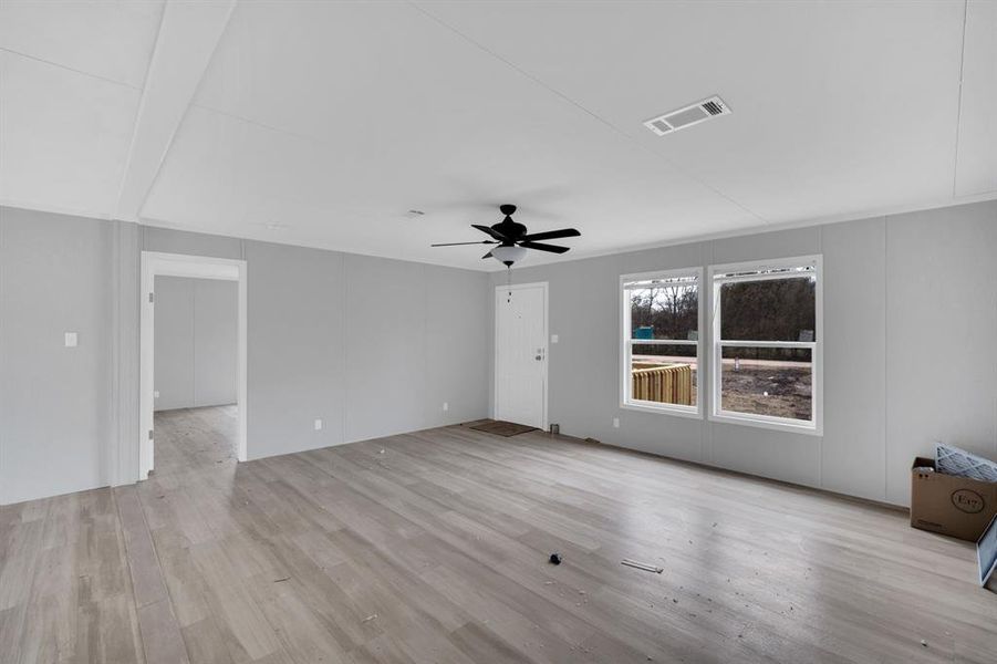 Unfurnished living room featuring a decorative wall, light wood finished floors, and a ceiling fan