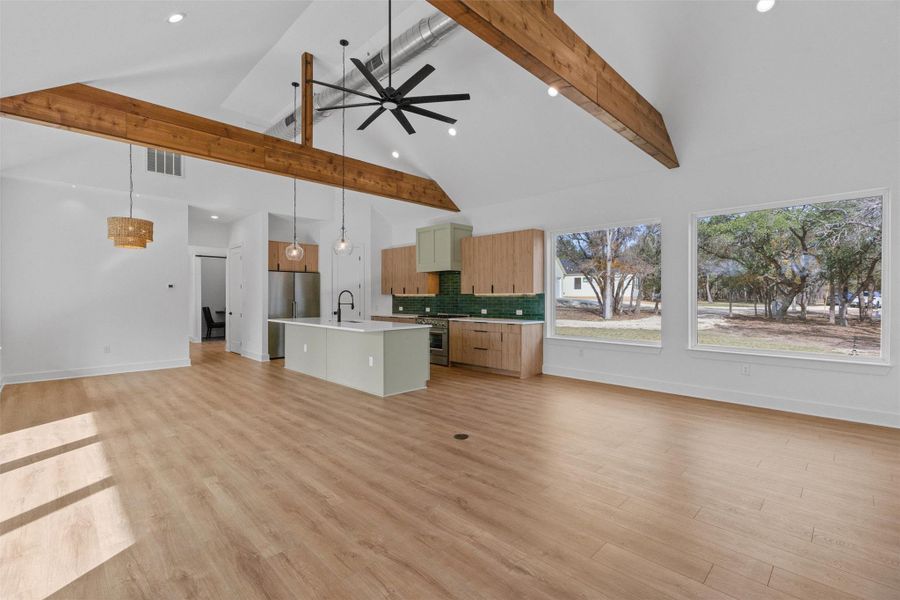 Seamless open living, kitchen, and dining with vaulted ceilings, exposed beams, and expansive sliders that open to lush outdoor views Seamless open living, kitchen, and dining with vaulted ceilings, exposed beams, and expansive sliders that open to lush outdoor views