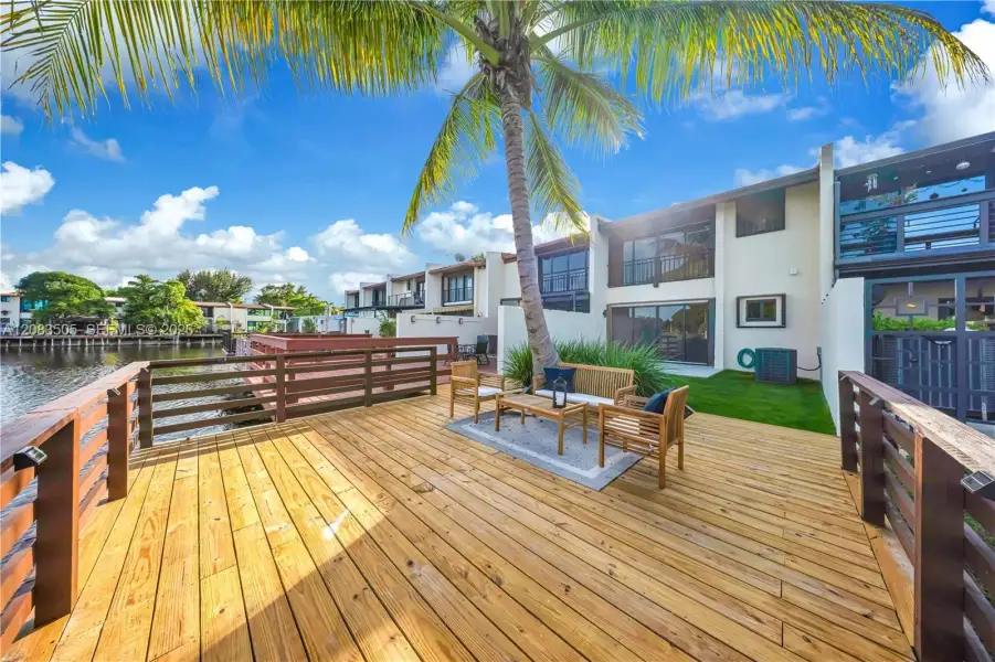 Waterfront deck featuring wood-finish decking, horizontal slat railings, and integrated lighting, accompanied by a manicured lawn Waterfront deck featuring wood-finish decking, horizontal slat railings, and integrated lighting, accompanied by a manicured lawn