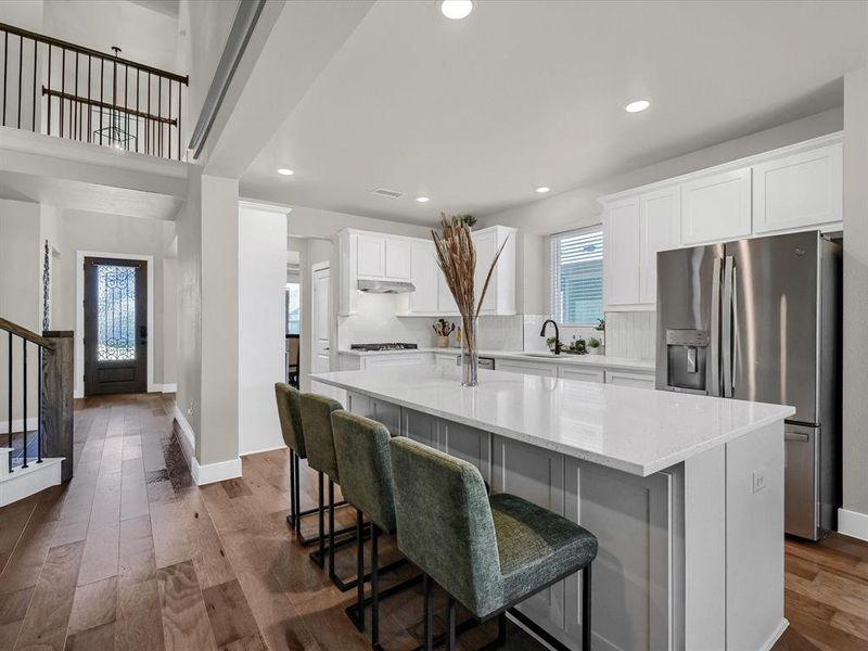 Kitchen featuring stainless steel fridge, a kitchen island, a kitchen breakfast bar, white cabinetry, and dark hardwood / wood-style floors Kitchen featuring stainless steel fridge, a kitchen island, a kitchen breakfast bar, white cabinetry, and dark hardwood / wood-style floors