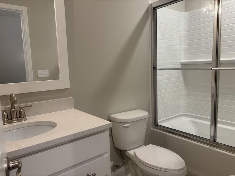 Bathroom featuring vanity, toilet, and bath / shower combo with glass door