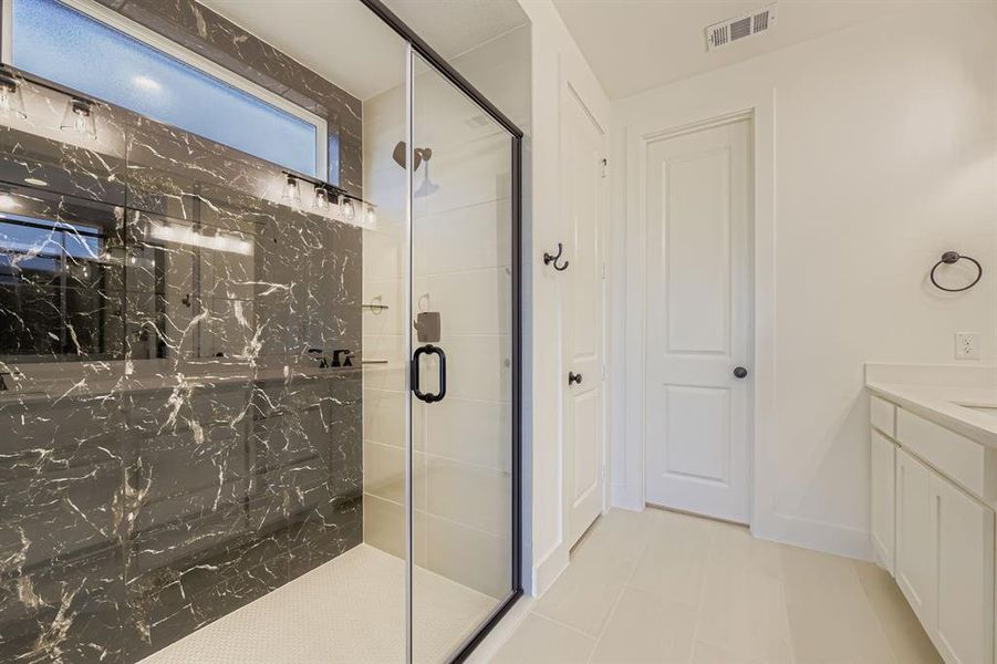 Full bath featuring a marble finish shower, vanity, and tile patterned flooring Full bath featuring a marble finish shower, vanity, and tile patterned flooring