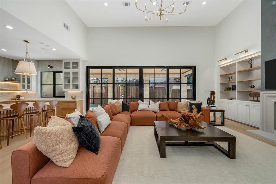 Spacious living area featuring high ceilings, wood-finish flooring, and built-in shelving