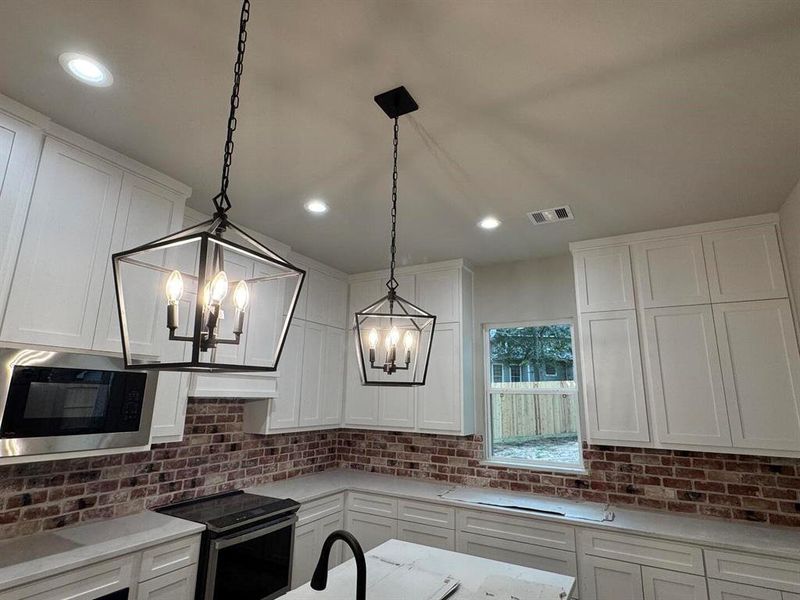 Farmhouse Lantern Chandeliers over the Island, Whitewashed Red Brick on the Back Splash, Custom Kitchen Cabinets to the Ceiling *Paper covering the Counter*