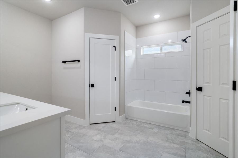 This modern bathroom features a sleek design with a bathtub-shower combo, white subway tiles, and a large vanity with ample counter space. It includes a small window for natural light and elegant black fixtures, offering a clean and contemporary look. This modern bathroom features a sleek design with a bathtub-shower combo, white subway tiles, and a large vanity with ample counter space. It includes a small window for natural light and elegant black fixtures, offering a clean and contemporary look.