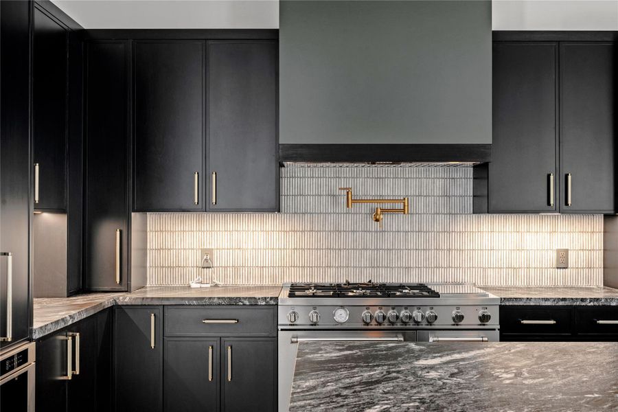 Kitchen featuring dark cabinetry, dark stone countertops, and decorative backsplash