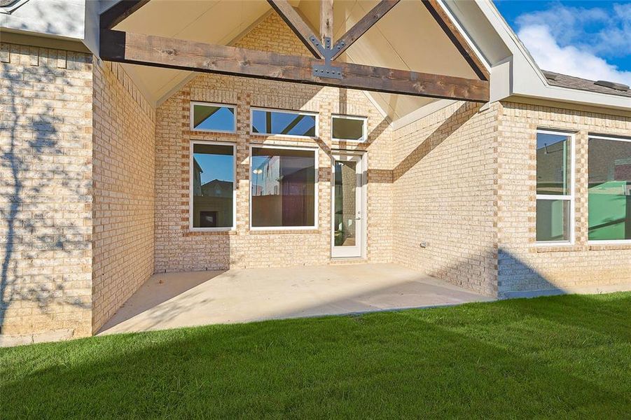 Property entrance featuring a lawn and a patio area