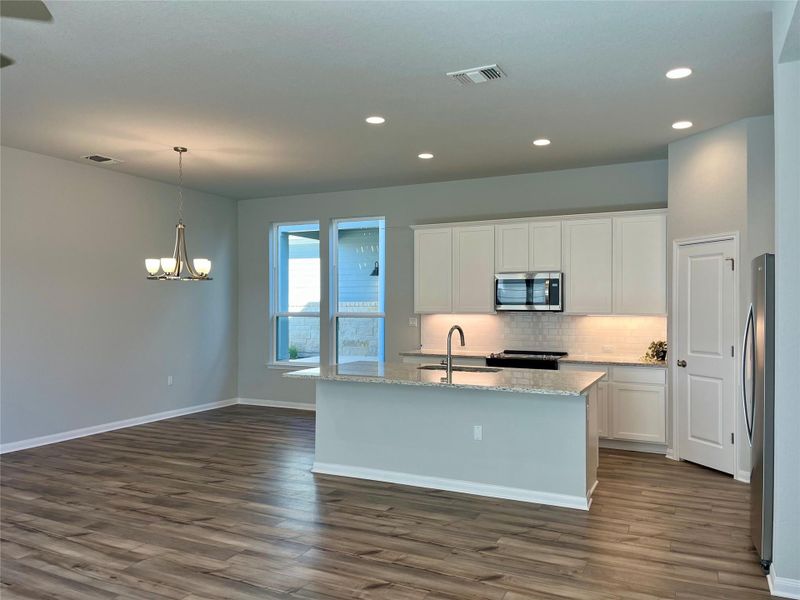Kitchen with white cabinets, a center island with sink, appliances with stainless steel finishes, and recessed lighting