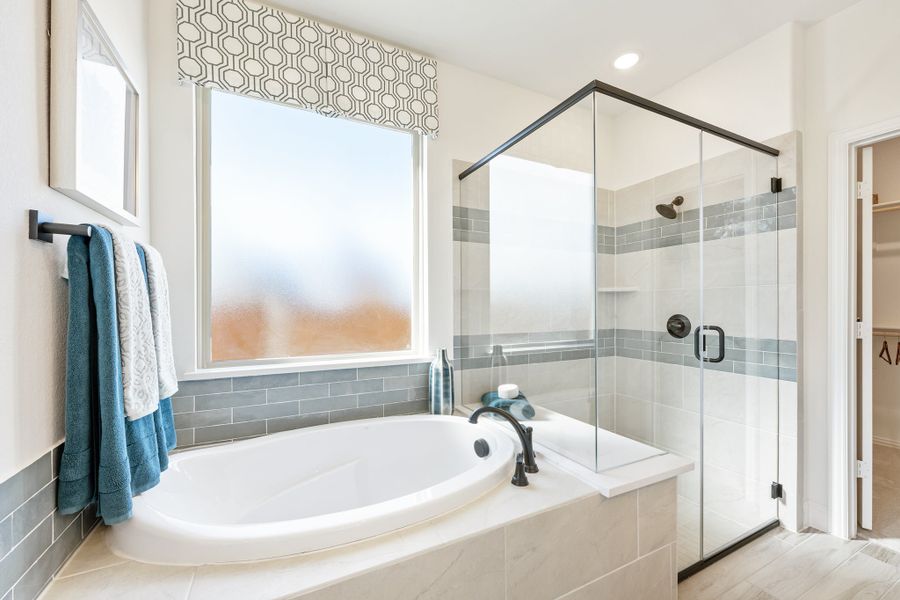 Master bathroom with soaking tub, glass-enclosed shower, and gray subway tile accents