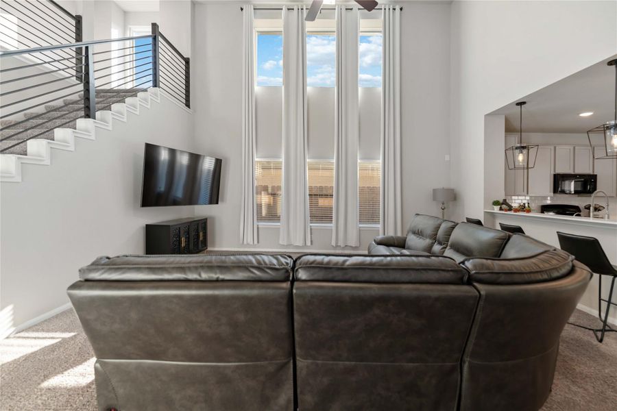 Spacious gathering area with elegant window treatments, ceiling fan, and an inviting layout designed for relaxation and entertaining. Spacious gathering area with elegant window treatments, ceiling fan, and an inviting layout designed for relaxation and entertaining.