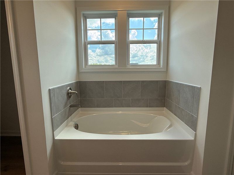 A deep soaking tub awaits under a bright window, p A deep soaking tub awaits under a bright window, p