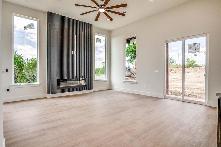 Unfurnished room featuring ceiling fan, plenty of natural light, and light wood-style floors