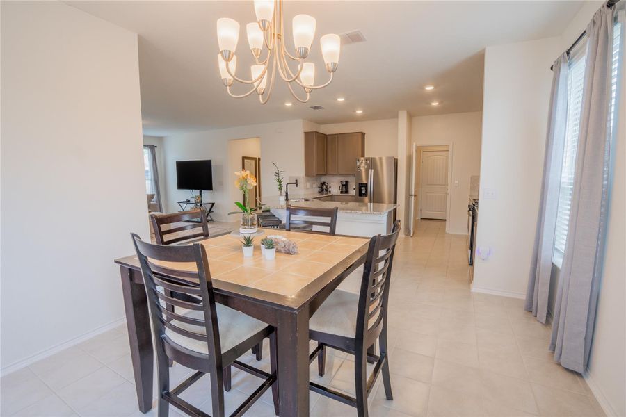 Dining area featuring tile flooring, a multi-bulb chandelier, and an open layout to the kitchen and living spaces Dining area featuring tile flooring, a multi-bulb chandelier, and an open layout to the kitchen and living spaces