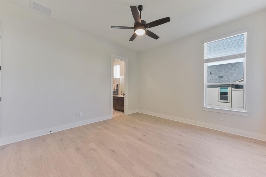 Unfurnished bedroom featuring light wood-type flooring, a ceiling fan, and ensuite bath