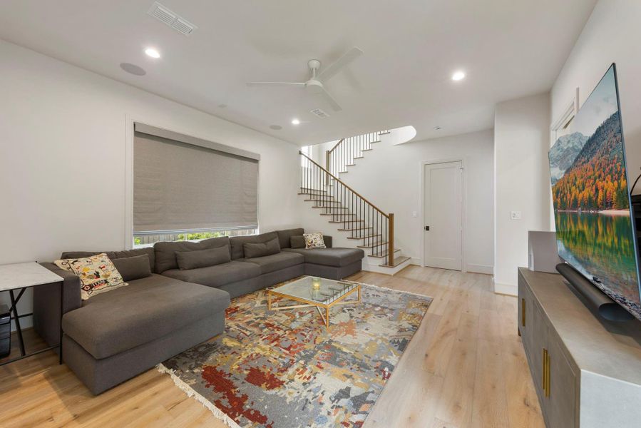 Hard to find downstairs game room or family room featuring wood flooring, a large picture window, and open access to the staircase—creating a comfortable space for relaxing, entertaining, or movie nights.